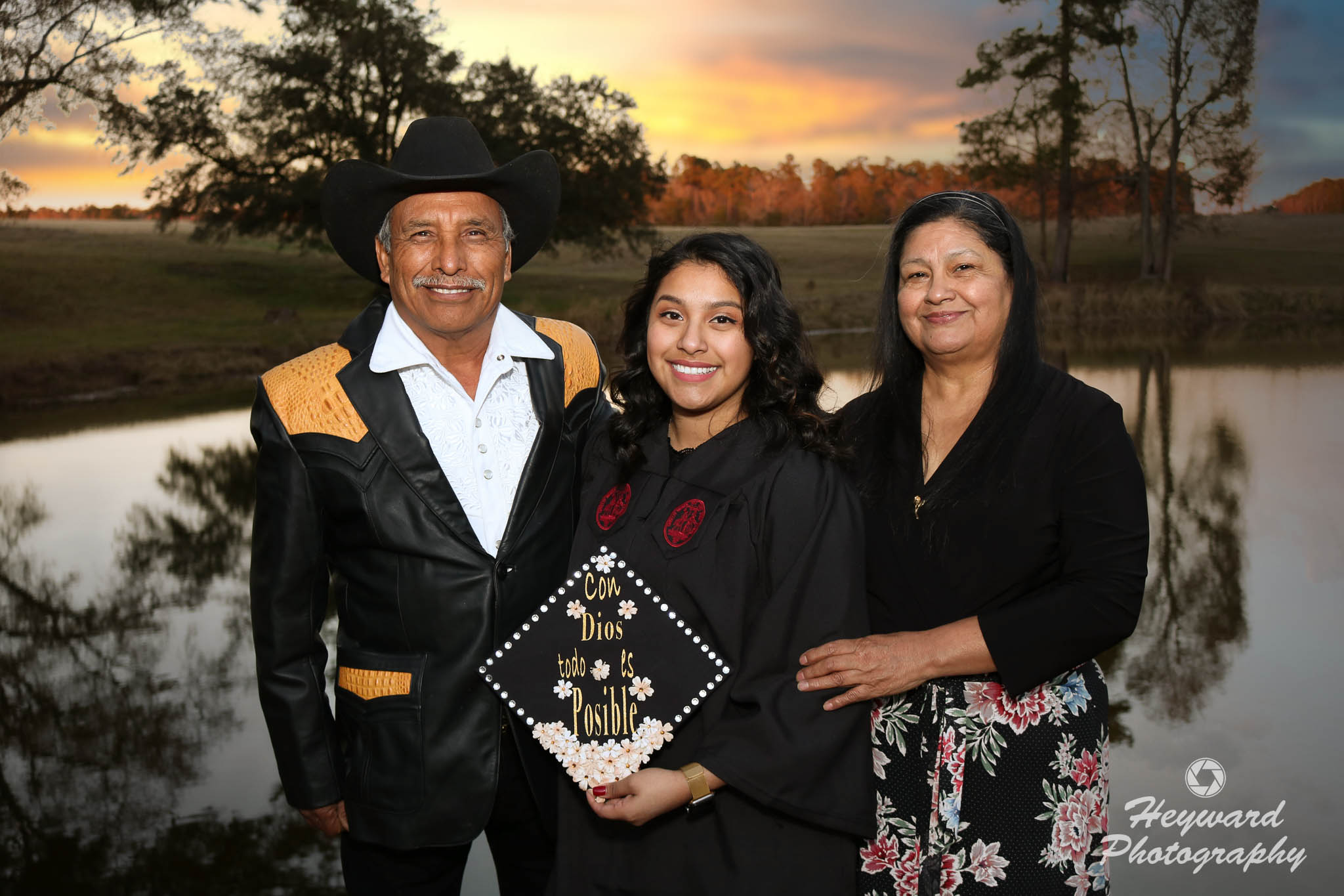 Latino family in front of a lake with college graduate.